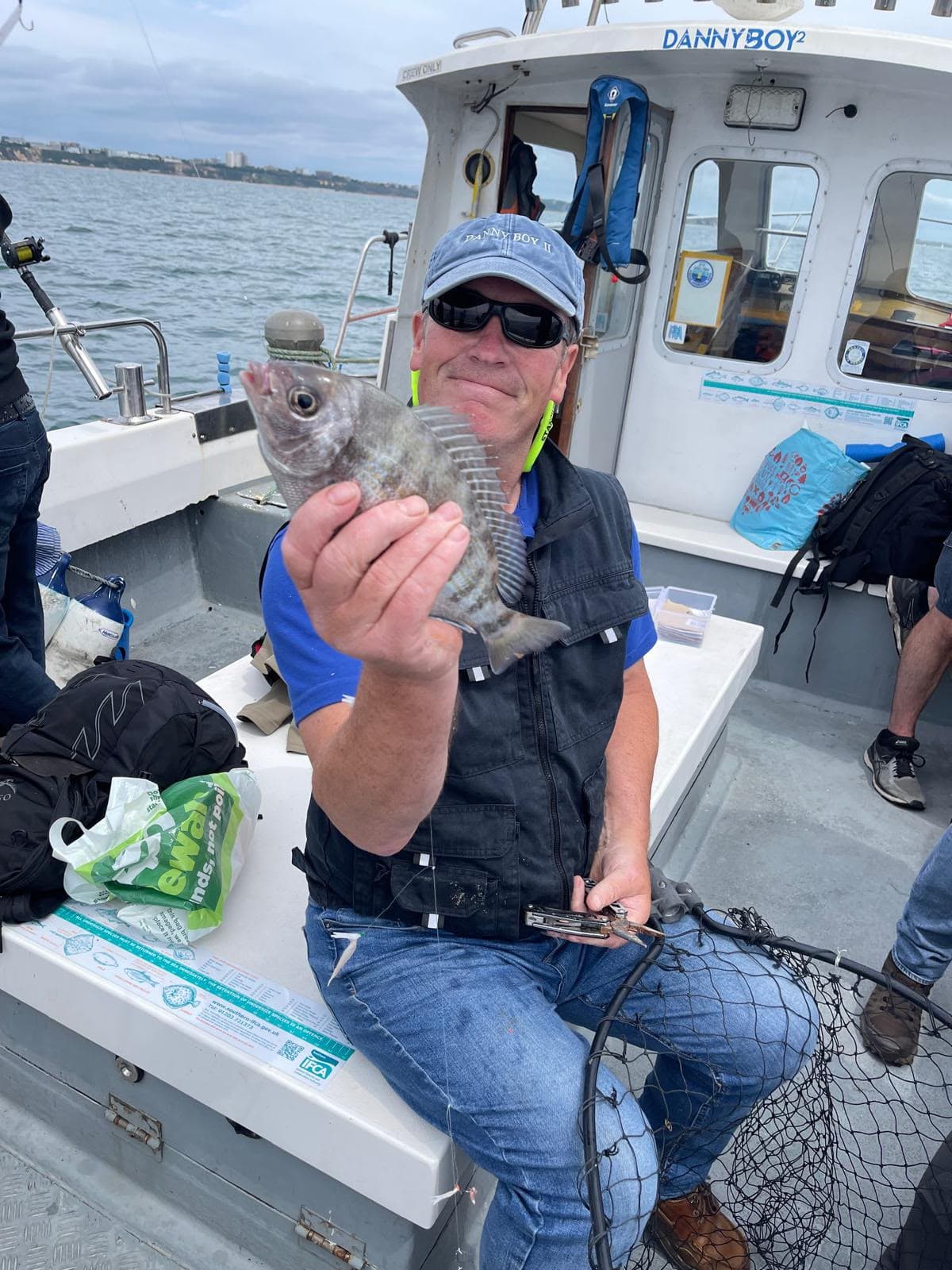 Angler holding up a freshly caught fish on deck
