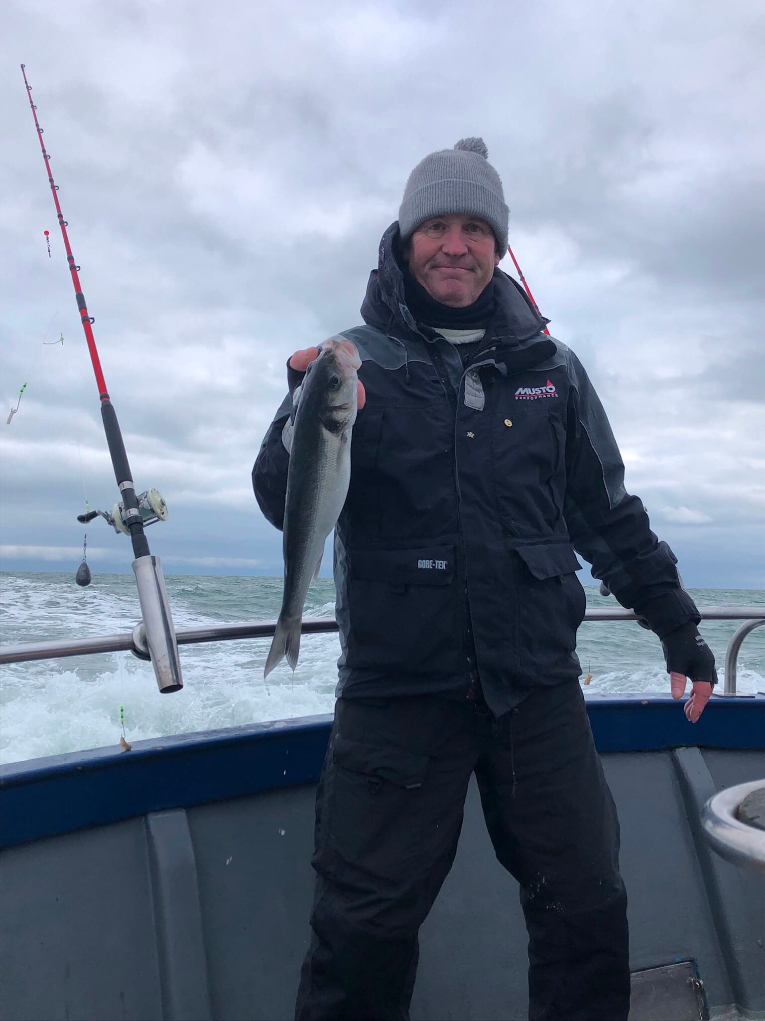Fisherman showing off a catch on a choppy sea